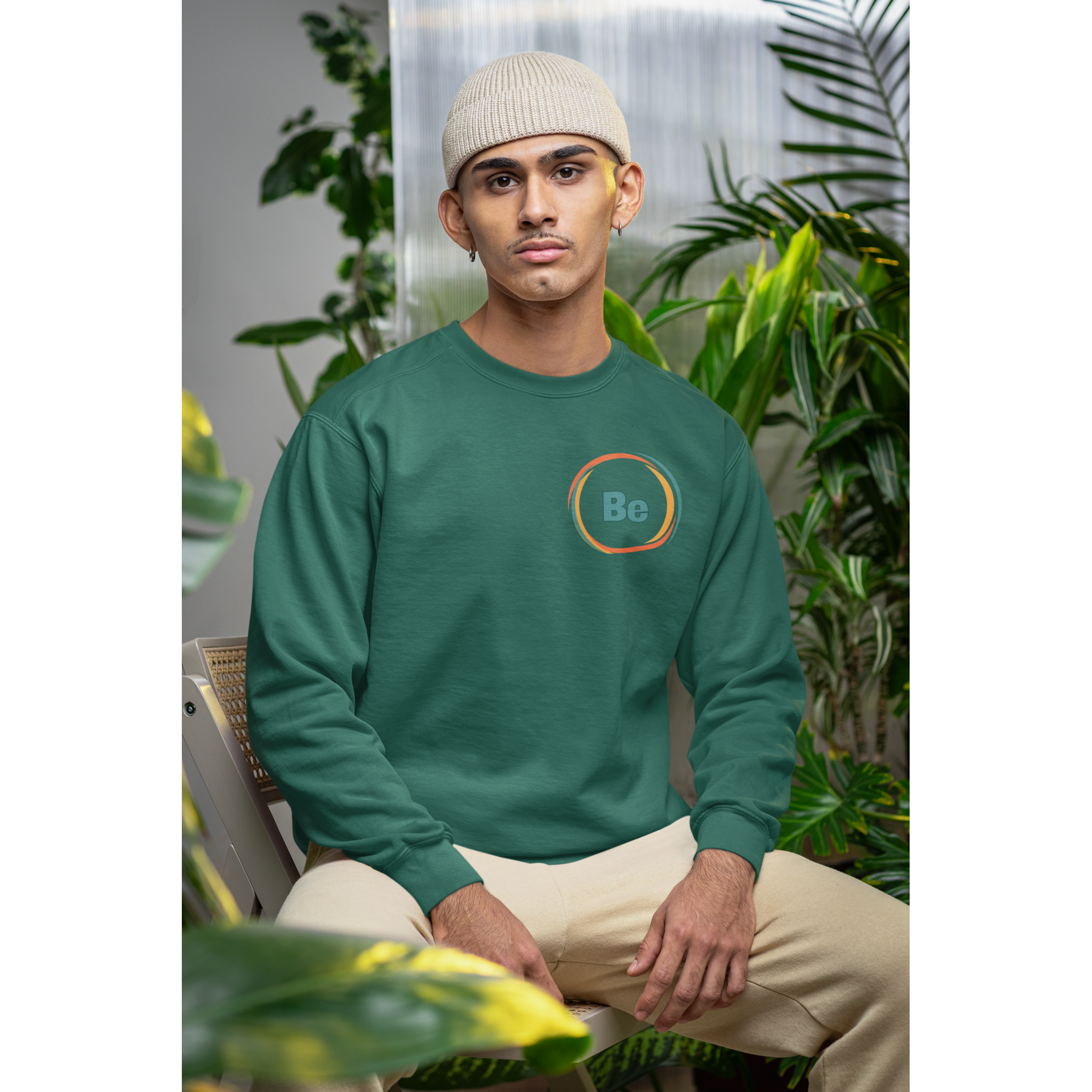 Person wearing a green sweatshirt with a logo sitting among plants