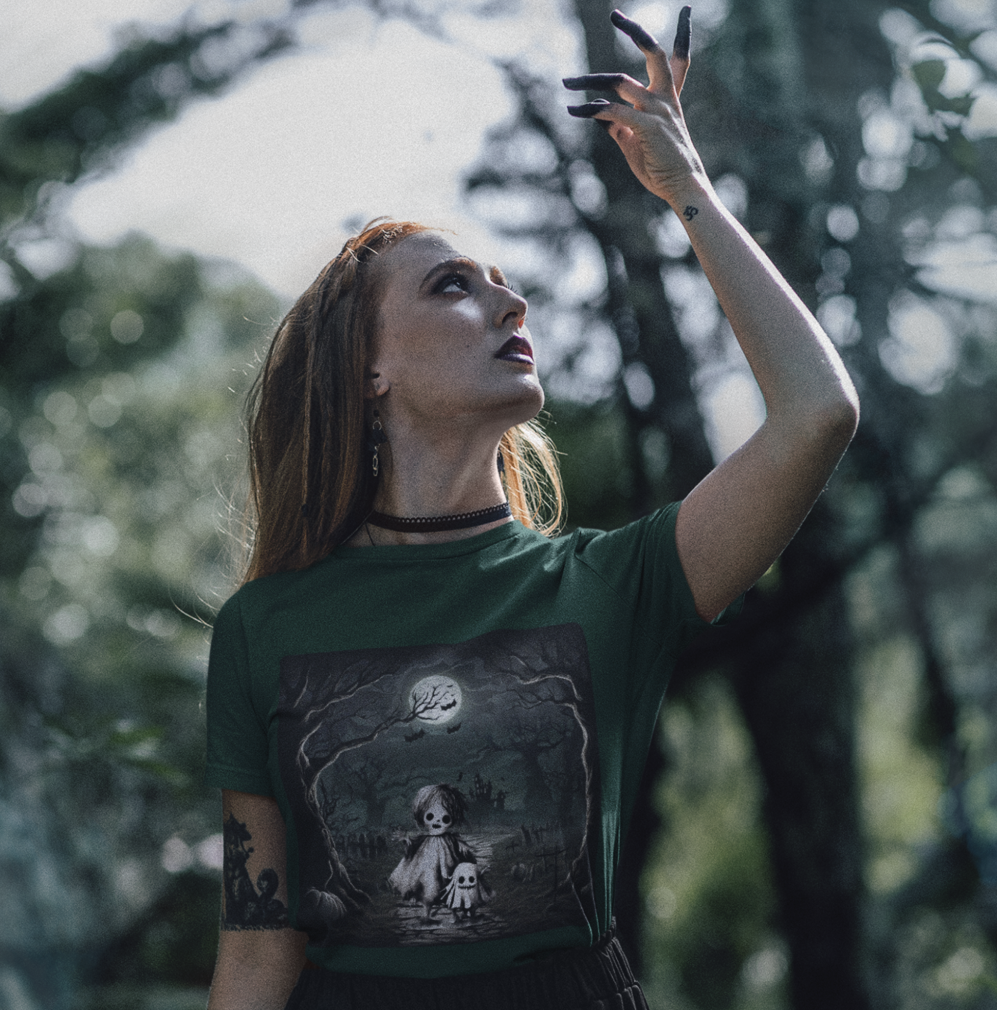 woman wearing a green t-shirt with a ghost and skeleton graphic design
in a forest.