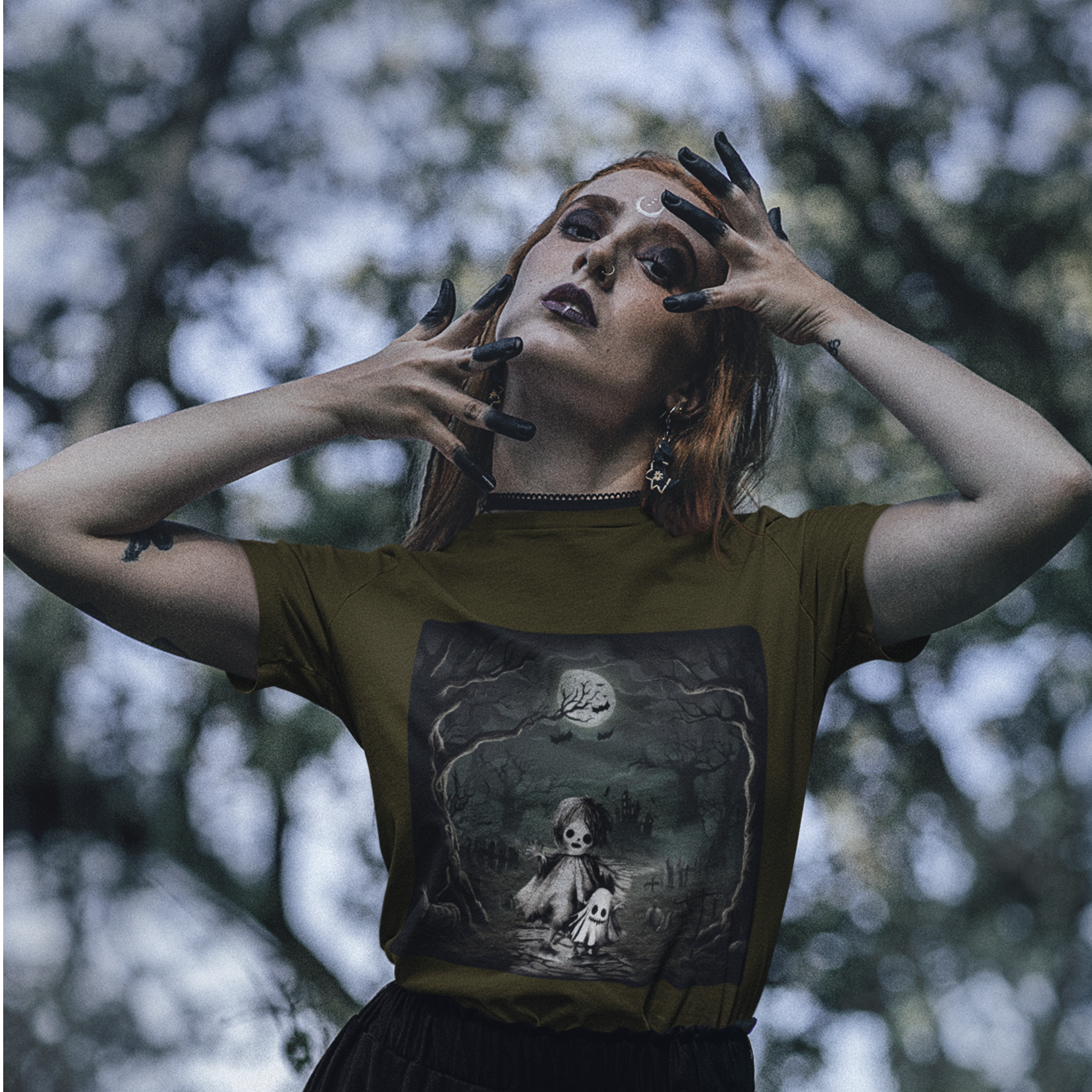 Person wearing a t-shirt with a graphic design of a doll in a forest, standing outdoors with trees in the background.