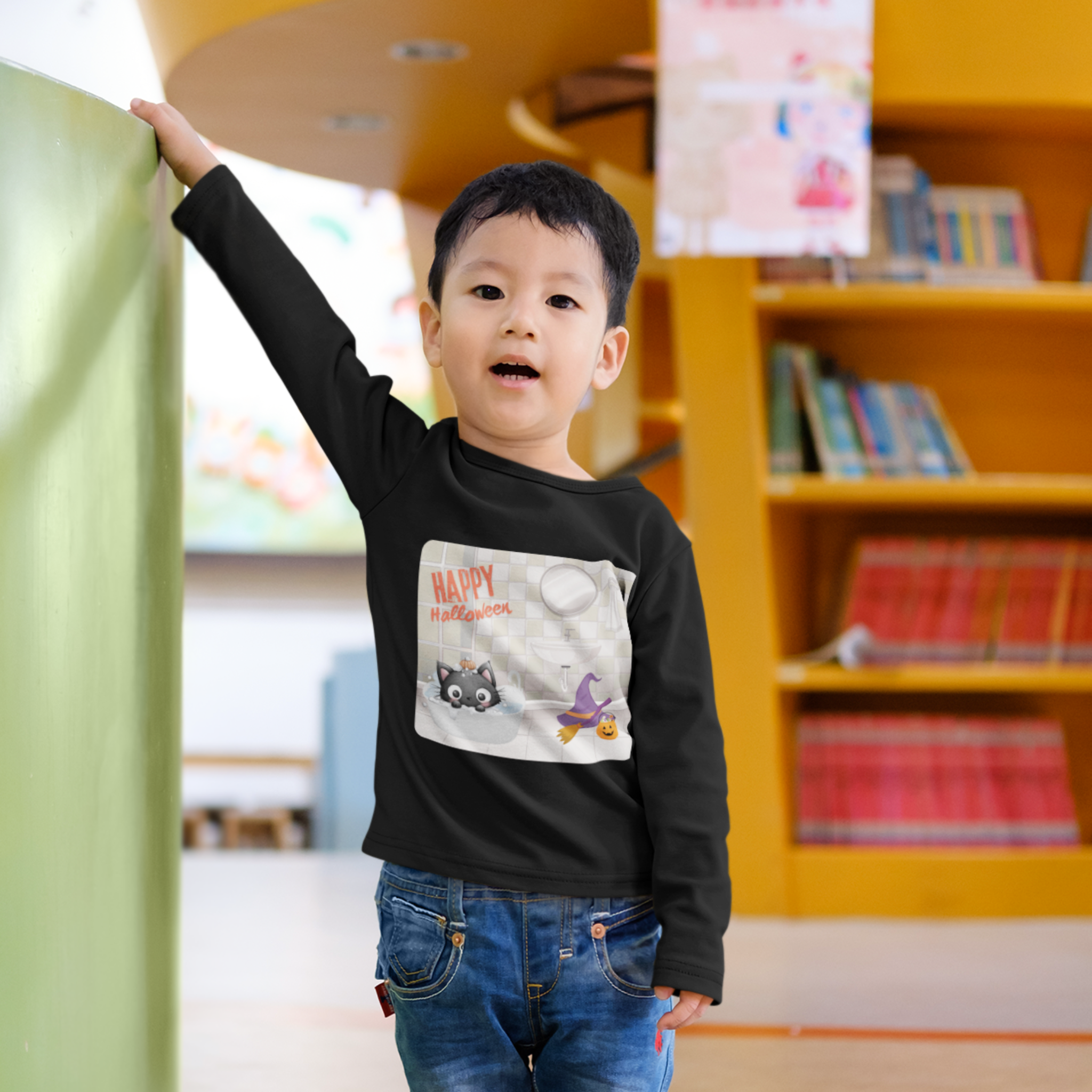 Child in a black shirt with a graphic design standing in a room with bookshelves and colorful decorations.