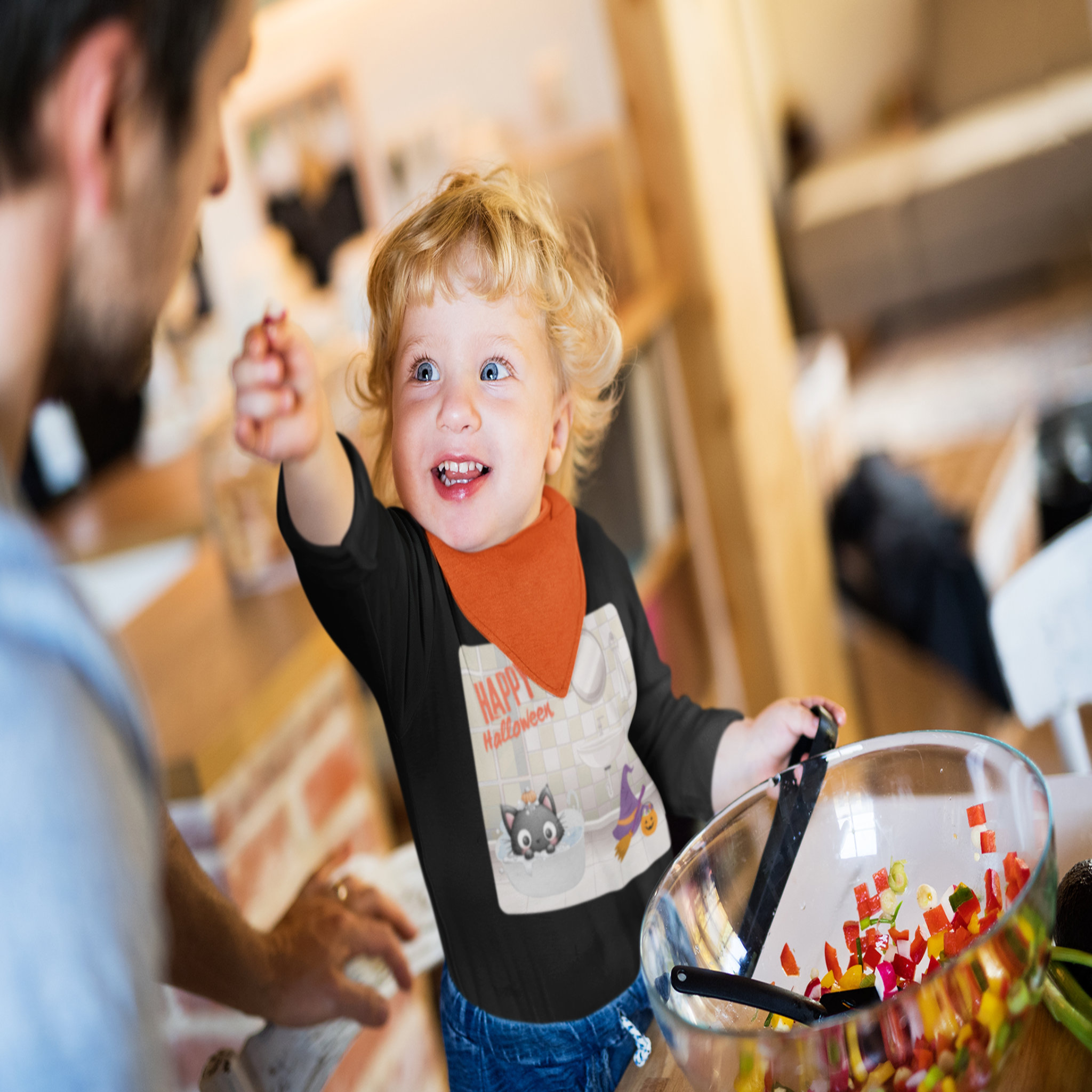 Child wearing a black shirt with a graphic design, standing next to a glass bowl filled with colorful items.