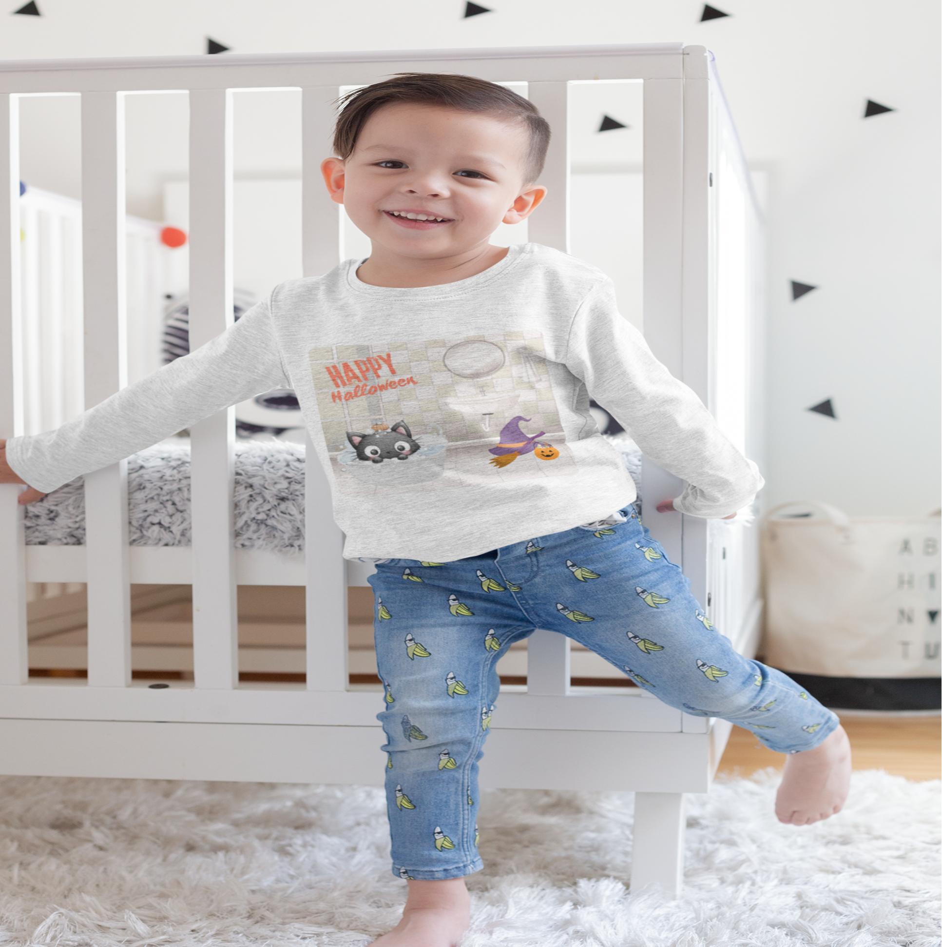 Child standing in a room with a crib and decorative triangles on the wall