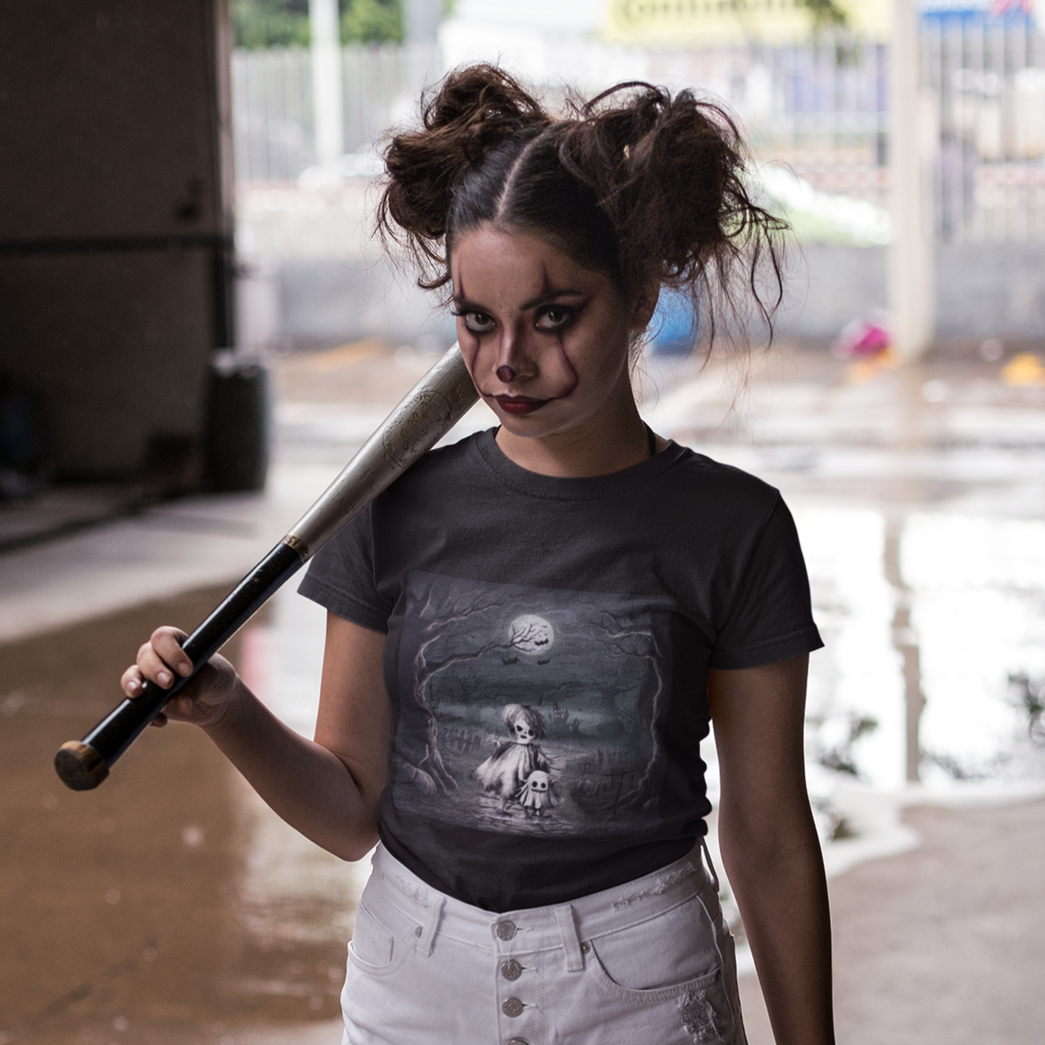 Person wearing a black t-shirt with a graphic design, holding a baseball bat.