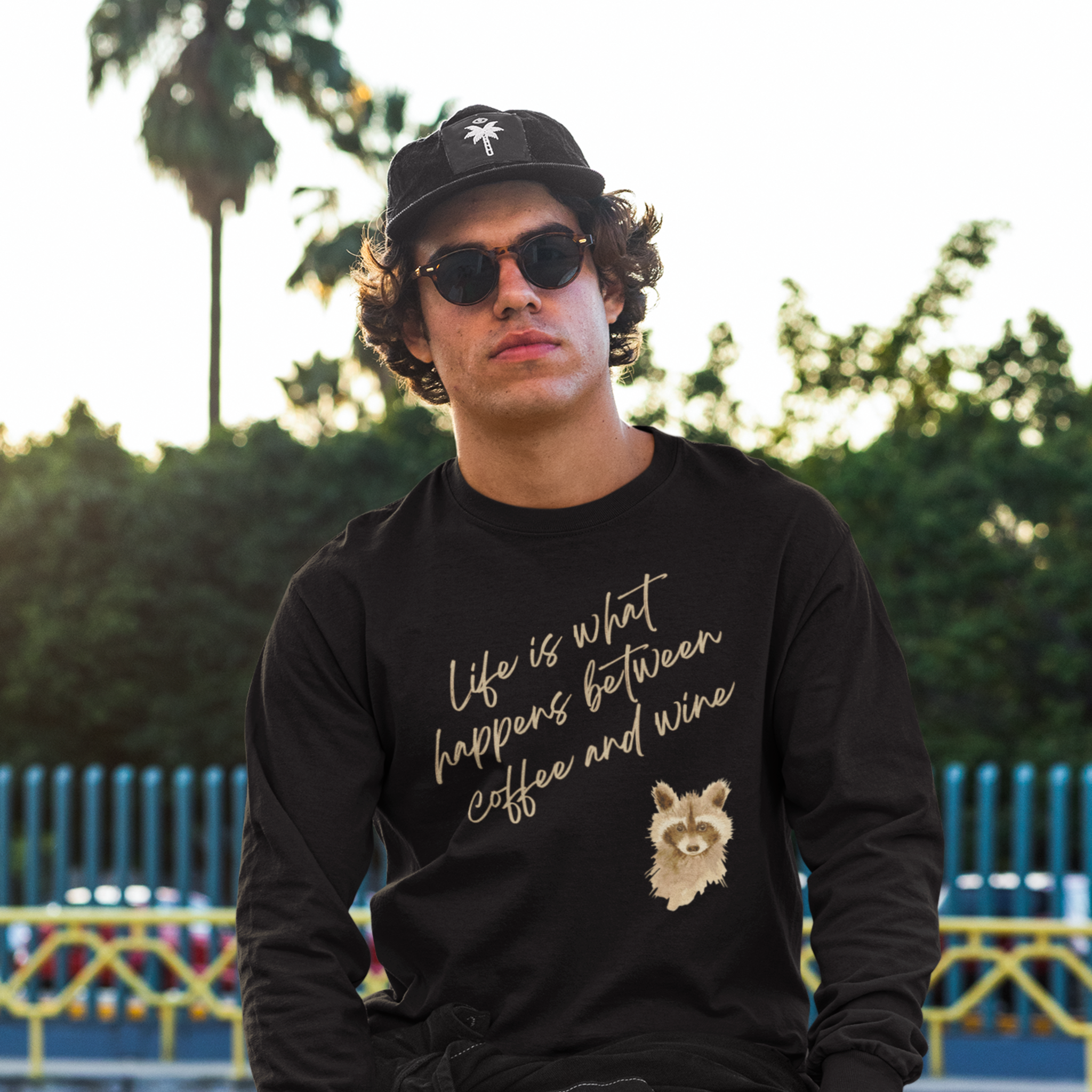 Man wearing a black sweatshirt with text and a wolf graphic, outdoors.