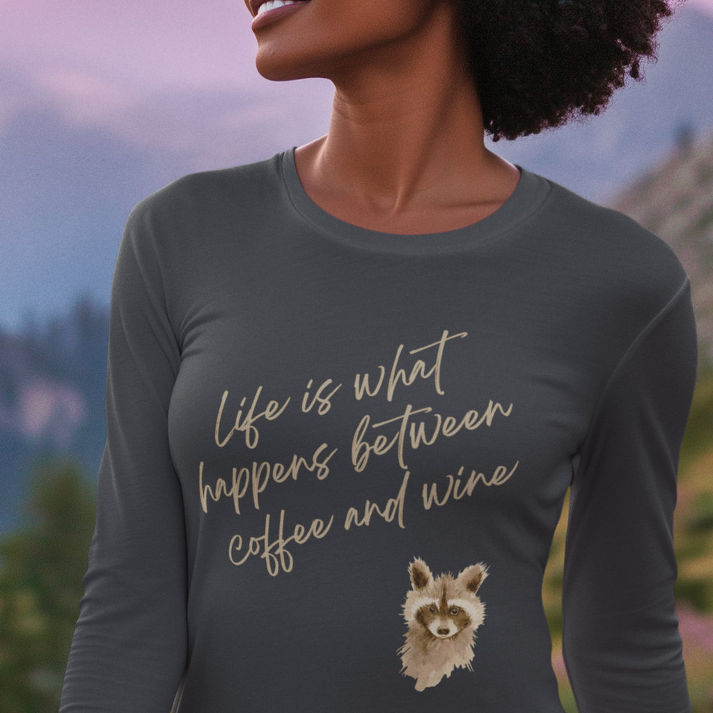 Person wearing a dark gray long-sleeve shirt with a raccoon illustration and text in a scenic outdoor setting.