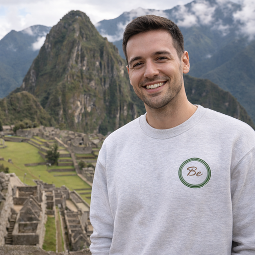 Man wearing a gray sweatshirt with a logo in front of Machu Picchu